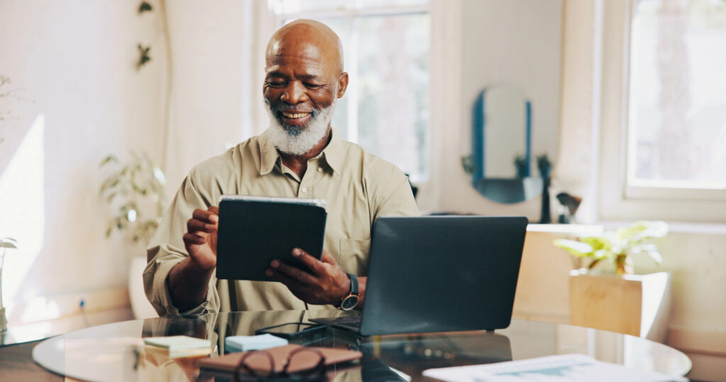 Business owner reviewing information on a tablet beside a laptop